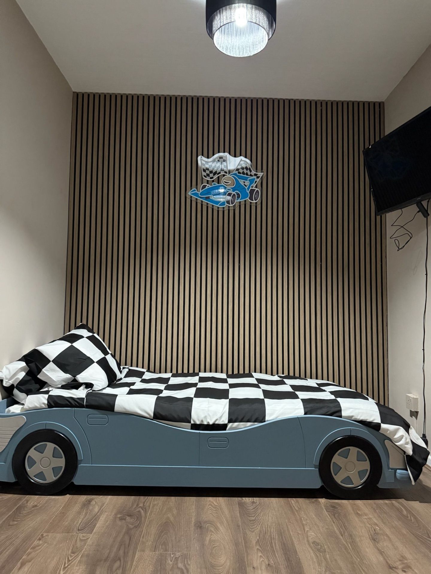 Younger boy's bedroom after: slatted feature wall, blue racing car bed and chequered flag bedding