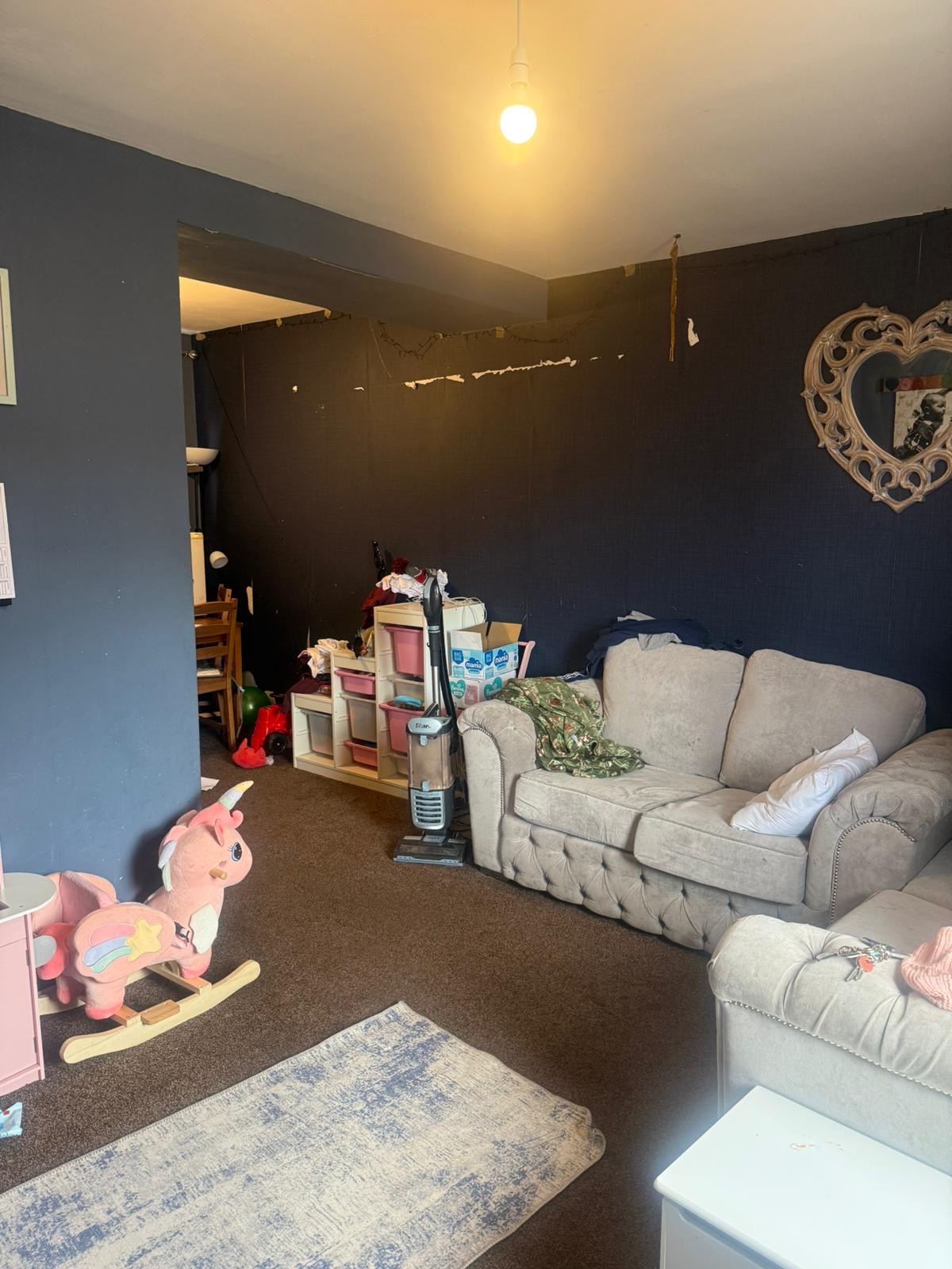 Beth's living room before: dark navy walls, peeling paper, cluttered furniture