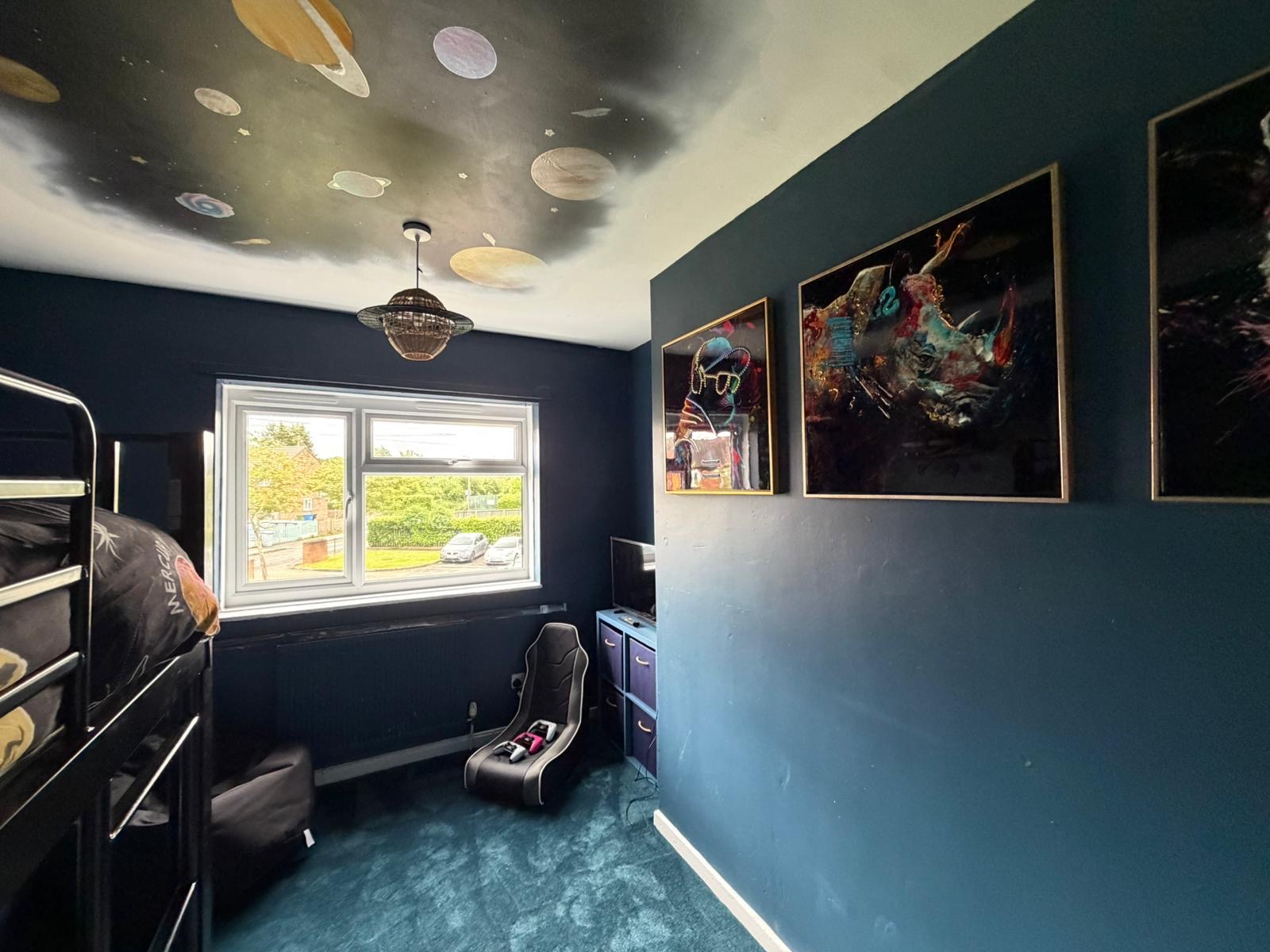 Boy's bedroom after: deep blue walls and a hand-painted solar system ceiling mural
