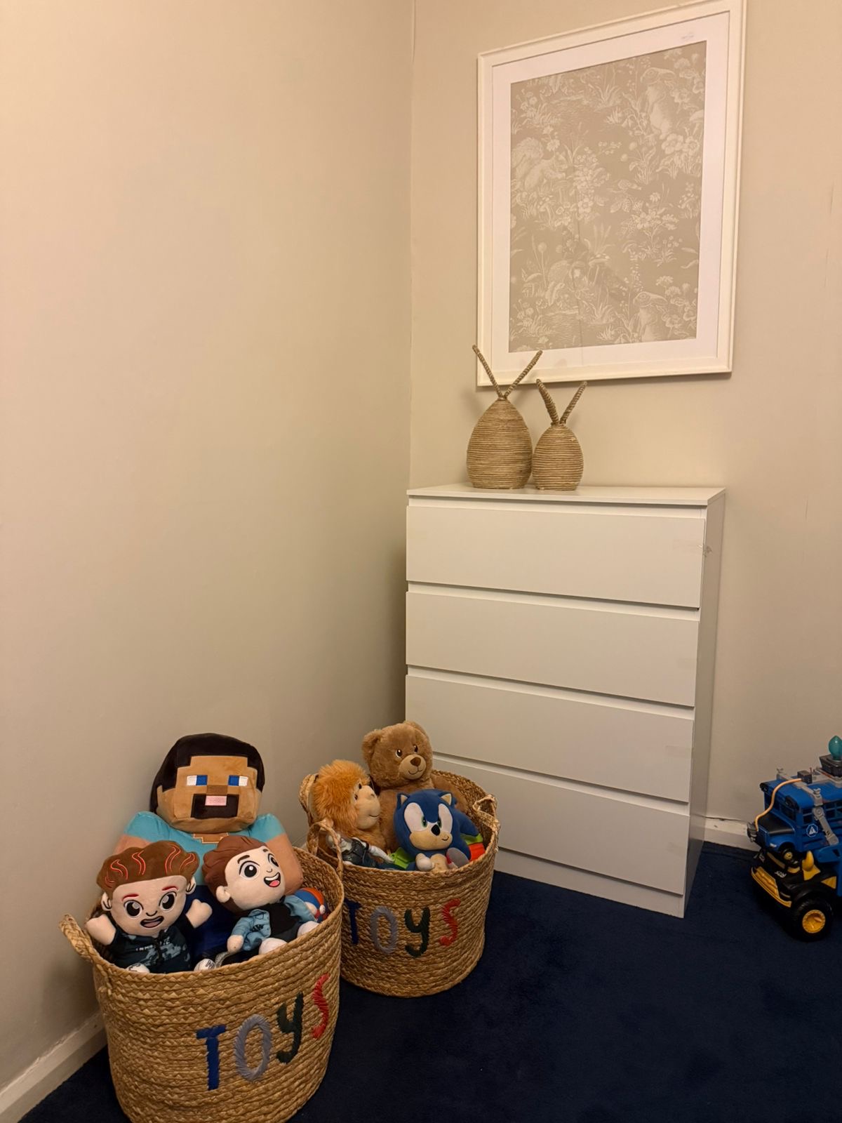 The boys' room: toy baskets sorted with their favourite characters, framed wallpaper print, neat chest of drawers