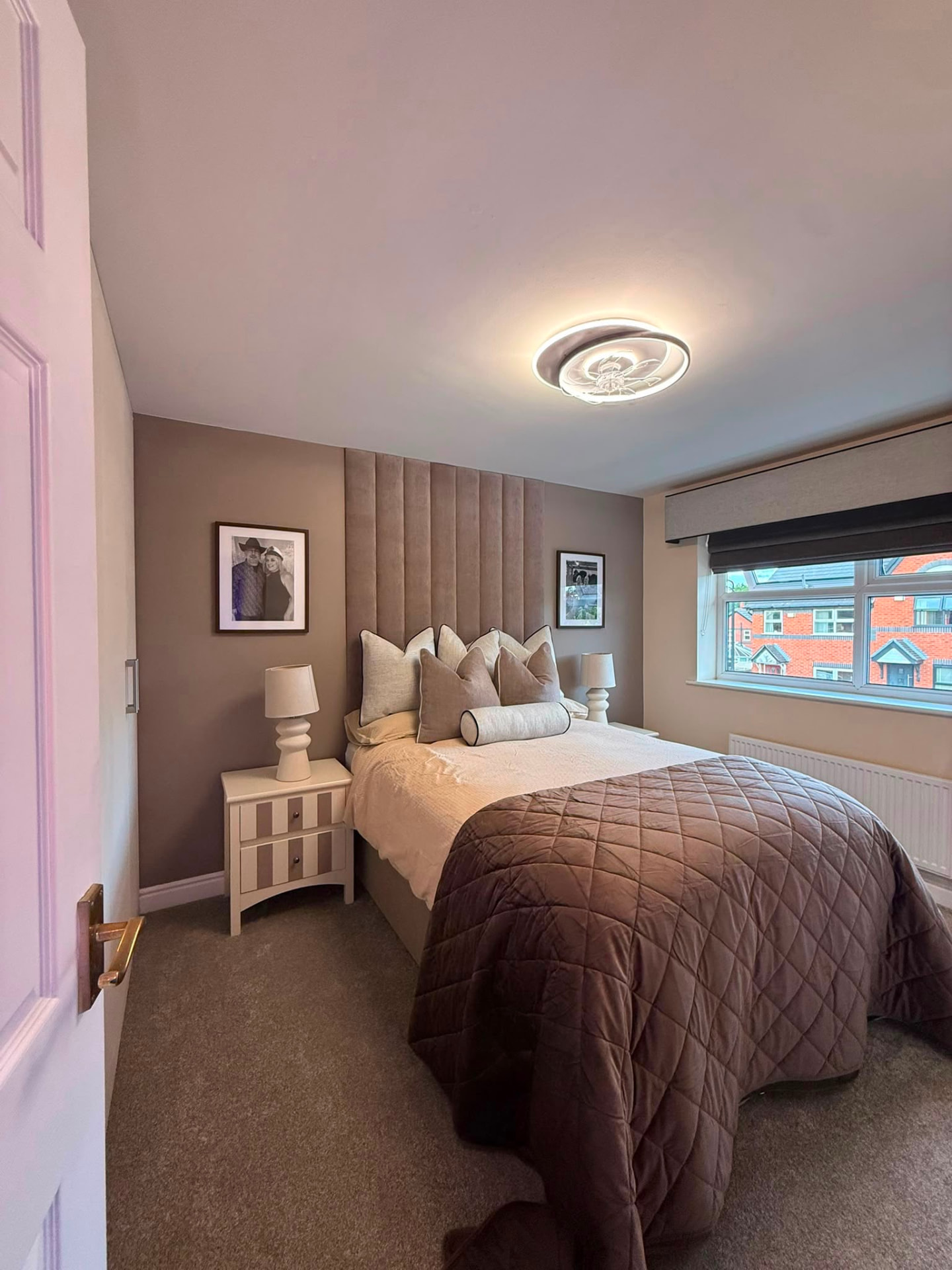 The transformed main bedroom: panelled feature wall, quilted bedding and matching bedside lamps