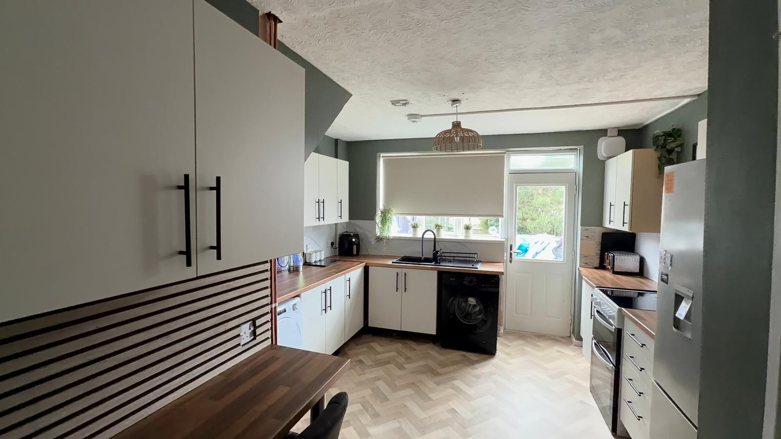 Sarah's kitchen after: sage walls, white shaker units, wood worktops and herringbone floor