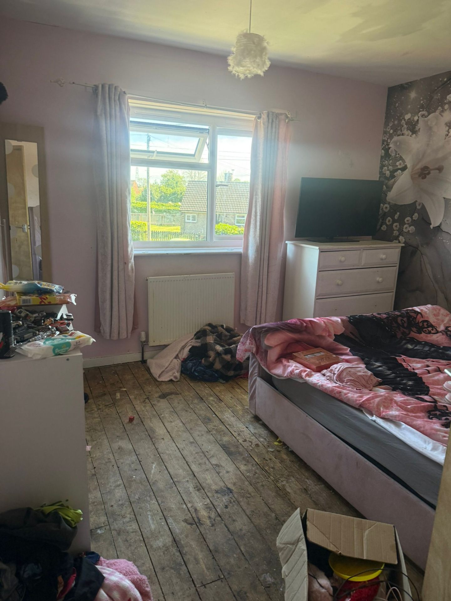 Sarah's bedroom before: bare floorboards, faded pink walls and cluttered surfaces