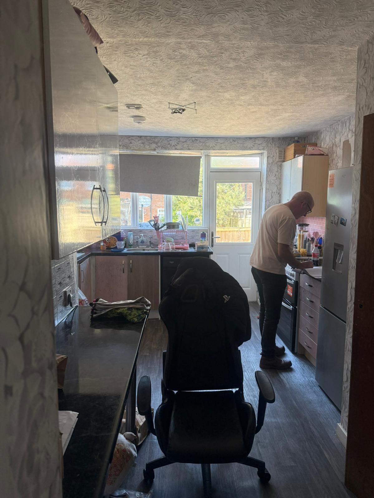 Sarah's kitchen before: textured wallpaper, mismatched units and crowded worktops