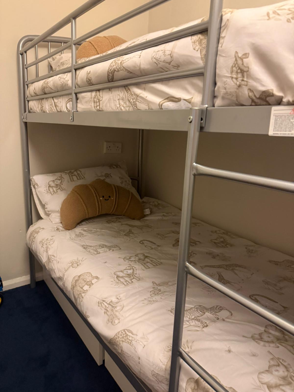 A child's bedroom after: tidy bunk beds with soft safari bedding and a calm carpet