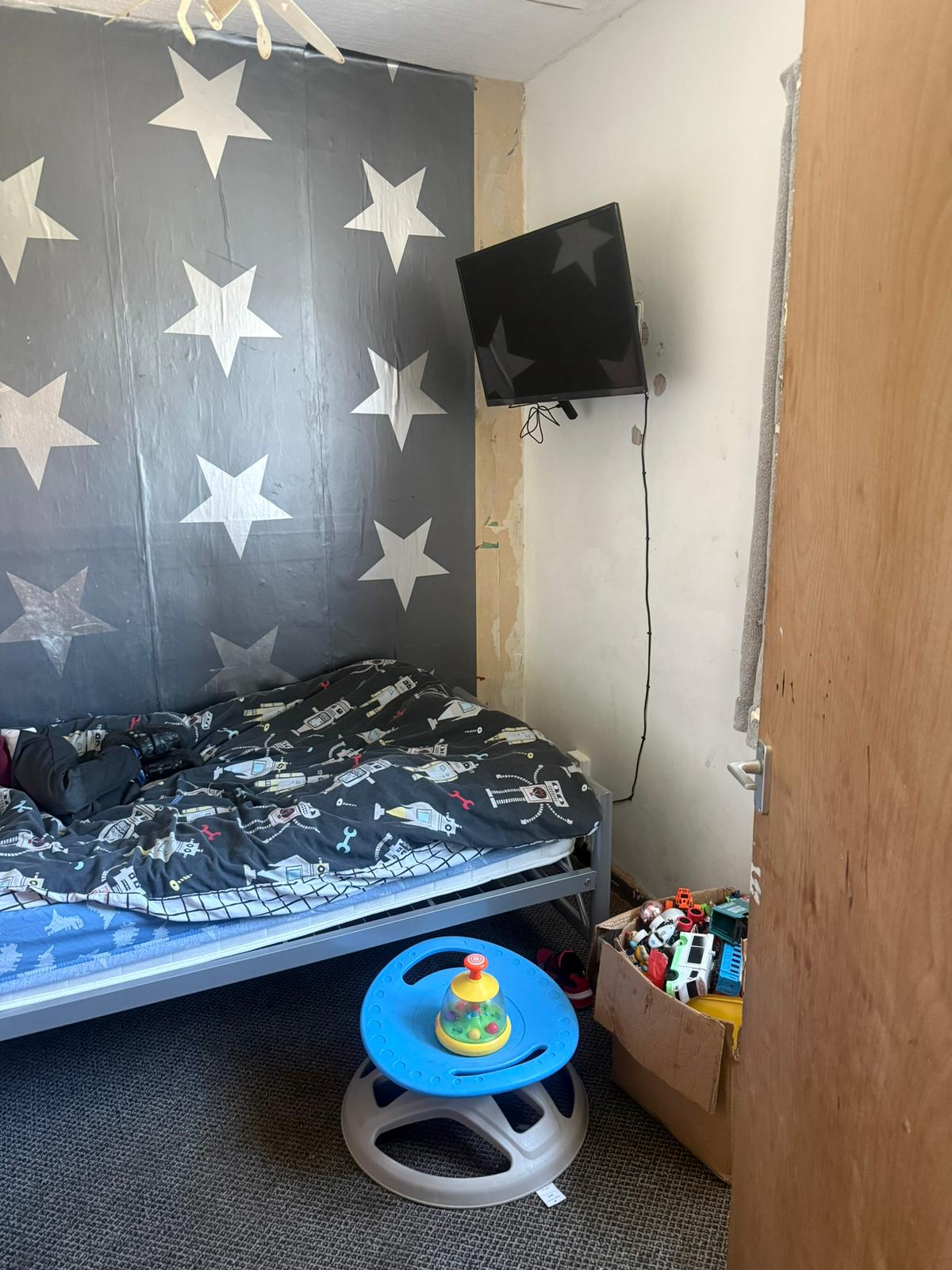 Younger boy's bedroom before: peeling star wallpaper and bare walls