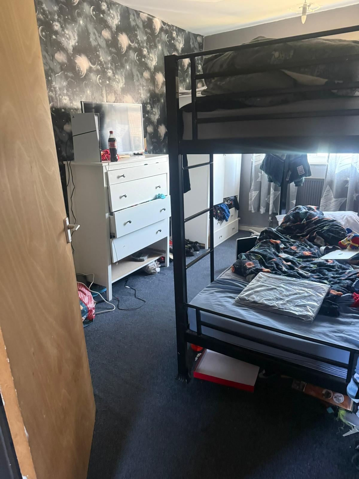 Boy's bedroom before: dark space wallpaper, bunk beds and cluttered floor