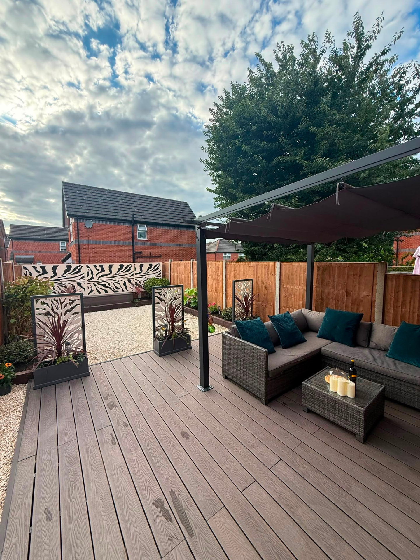 The new garden decking and pergola: composite boards, rattan corner sofa and decorative planters